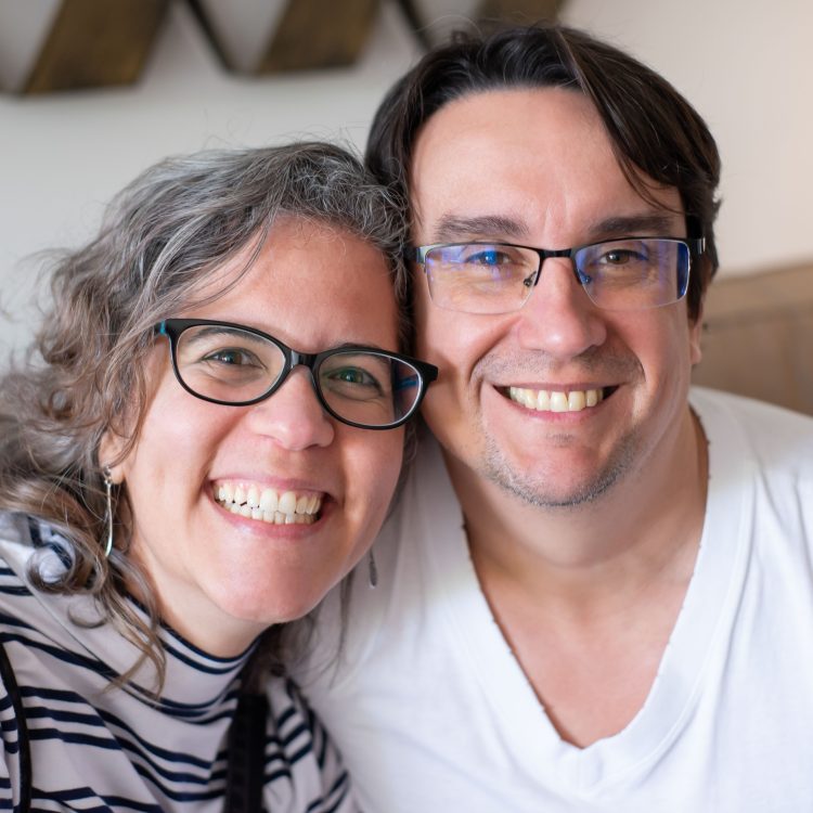 A smiling adult couple or family in a warm, natural setting.